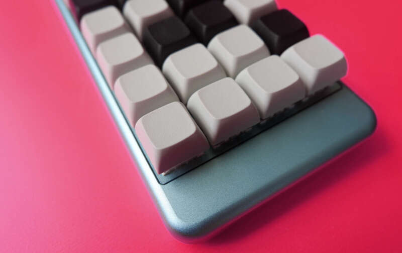 Close-up photograph of an XKDB4x keyboard with blue anodized case and black and white XDA-profile key caps