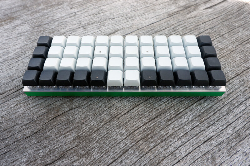 Photograph of a Planck keyboard with steel plate, green milled bottom, and black and white XDA-profile key caps